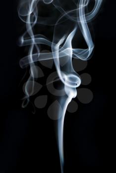 Photo of abstract smoke swirls on black background. Vertical shot.