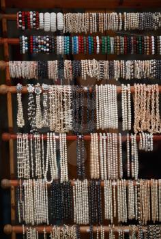 Pearl beads and jewelry hanging on wooden bars.