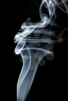 Curls of smoke abstract on a black background. Vertical shot.