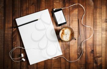 Responsive design mock up. Photo of blank stationery set. Paper, letterhead, coffee cup, smartphone, pencil and headphones on wooden table background. Top view.