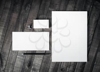 Photo of blank corporate identity. Branding mockup. Sheets of paper, letterhead, business cards, envelope and pencil on wooden table background. Blank stationery set. Mock up for ID. Top view.