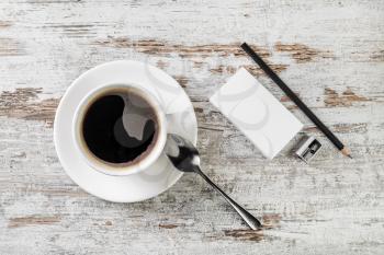 Still life with coffee. Coffee cup, bank business cards, spoon, pencil and sharpener on wooden table background. Top view.