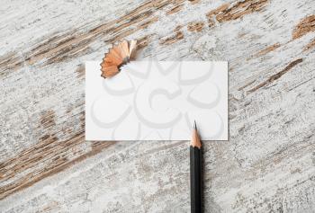 Photo of blank business card and pencil on vintage wood table background.