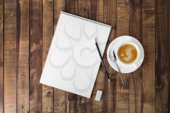 Photo of blank notebook, coffee cup, pencil and eraser on vintage wood table background. Stationery elements. Template for placing your design. Responsive design mockup.