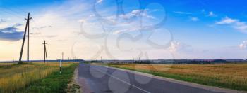 Panoramic rural landscape with an asphalt road and a heavenly sky. Evening in the countryside. Panorama shot.
