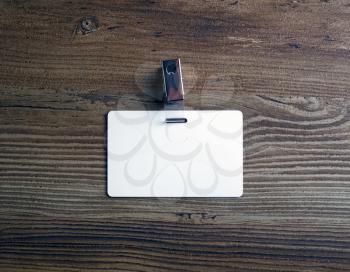 Photo of blank white plastic badge on vintage wooden table background. Blank id card. Top view.