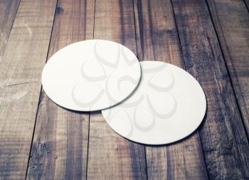 Two blank white beer coasters on vintage wooden table background. Responsive design mockup.