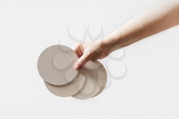 Female hand holding a blank beer coasters.