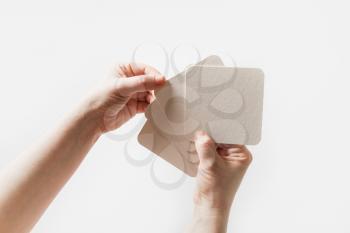 Female hands holding a blank square beer coasters.