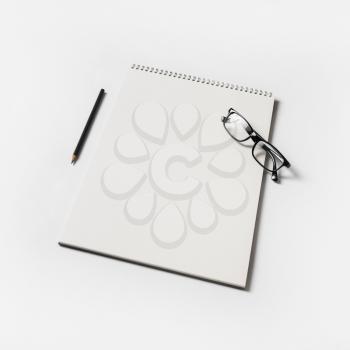 Album, glasses and pencil on white paper background. Blank sketchbook and stationery.