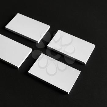 Four stacks of blank business cards on black paper background.