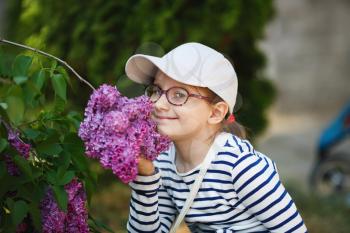 Girl smelling lilac flowers in the garden. Selective focus.