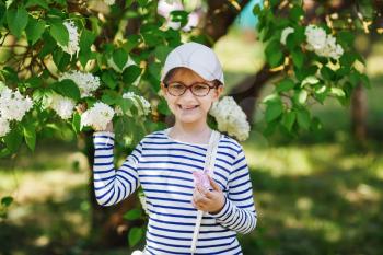Little girl child on a background of white lilac bush.