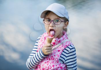 Child girl eats tasty ice cream outdoors.