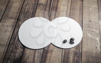 Two blank white beer coasters and coffee beans on vintage wood table background.