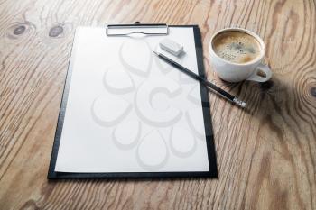 Blank stationery set. Clipboard with blank letterhead, coffee cup and pencil on wooden background. Mock up for your design.