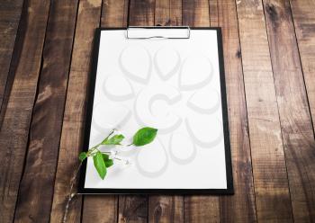 Paper clipboard, blank letterhead and cherry blossoms with green leaves on vintage wood table background. Responsive design mockup.