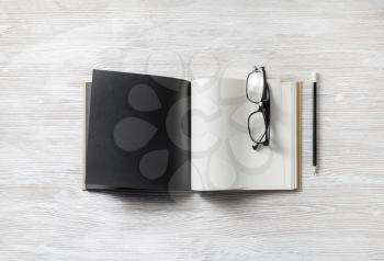 Mockup of opened blank book, pencil and glasses on light wooden background.