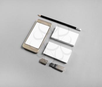 Blank business cards, pencil, usb flash drive and smartphone with blank screen on gray paper background. Smartphone and stationery