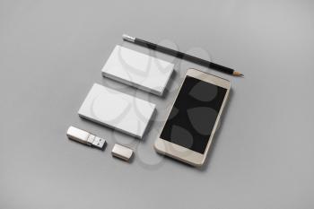 Gadgets and stationery. Mockup of blank business cards, pencil, usb flash drive and cellphone with blank screen on gray paper background.