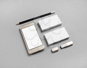 Cellphone and stationery on gray paper background. Blank business cards, pencil, smartphone and usb flash drive.