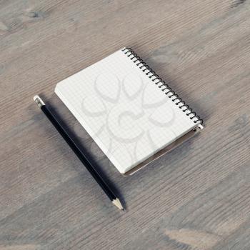 Blank notebook and pencil on wood table background.
