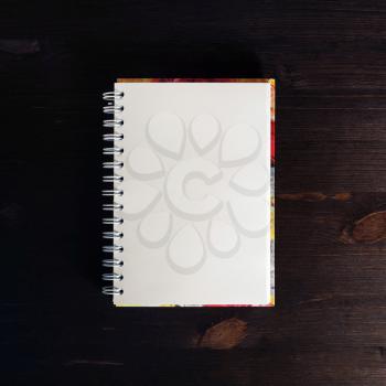 Blank spiral notebook on dark wooden background. Flat lay.