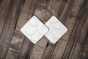Two blank square beer coasters on wood background. Flat lay.