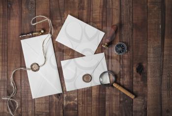 Vintage letter envelopes with golden wax seal, stamp, spoon, magnifier, compass and postcard on wooden background. Mock-up for your design. Flat lay.