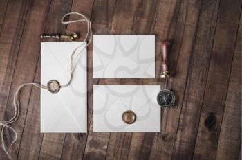 Blank paper envelopes with wax seal, stamp and stationery on vintage wood background. Flat lay.