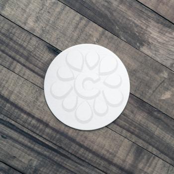 Photo of blank beer coaster on wood background. Flat lay.