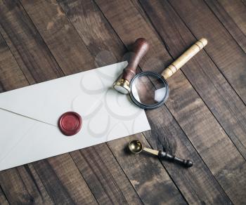 Vintage stationery mockup. Photo of blank envelope, sealing wax, stamp, magnifier and spoon on wood background. Template for placing your design.