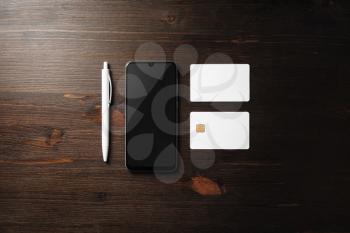 Corporate identity template on wooden background. Smartphone, business card, bank card and pen. Top view. Flat lay.