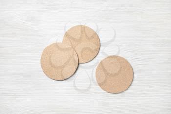 Blank cork beer coasters on light wooden background. Flat lay.