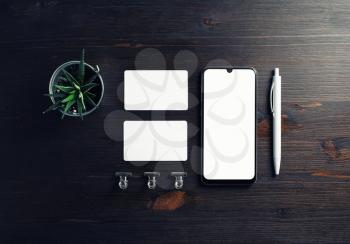 Corporate identity mockup. Smartphone, blank business cards, pen and plant on wooden background. Top view. Flat lay.
