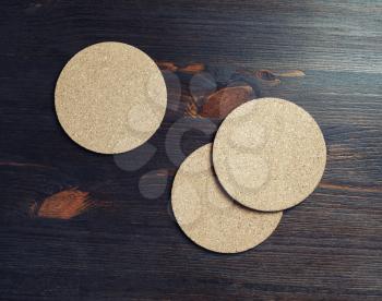 Photo of three blank cork beer coasters on wooden background.