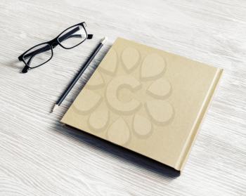 Blank closed notebook, pencil and glasses on light wooden background. Copy space for text.
