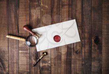 Blank paper envelope with red wax seal, stamp, spoon and magnifier on wooden background. Mockup for your design. Flat lay.