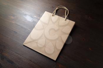 Blank disposable paper bag with rope handles on wood table background.