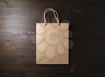 Blank brown paper bag with rope handles on wooden background. Flat lay.