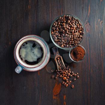 Coffee cup, roasted coffee beans and ground powder on wood kitchen table background. Top view. Flat lay.