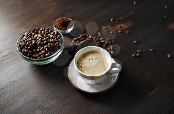 Still life with coffee cup, roasted coffee beans and ground powder on wooden kitchen table background.