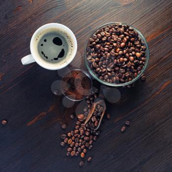Photo of coffee cup, coffee beans and ground powder on wood kitchen table background. Flat lay.