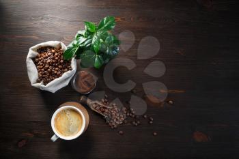 Making coffee. Photo of coffee cup, coffee beans, plant and ground powder on wooden background. Copy space for your text. Top view. Flat lay.