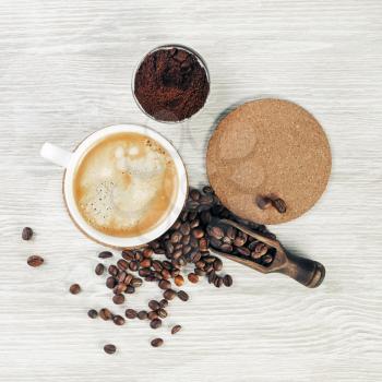 Photo of coffee cup, roasted coffee beans, ground powder and beer coaster on light wooden background. Flat lay.