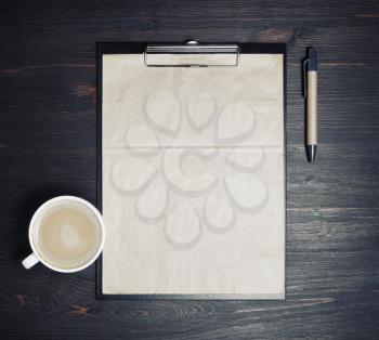 Photo of blank kraft stationery: letterhead, checklist, pen and coffee cup on wooden background. Responsive design mockup. Top view. Flat lay.