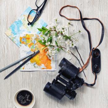 Planning vacation trip with map, binoculars, glasses, pencils, coffee cup and flowers. Travel or vacation concept. Flat lay.
