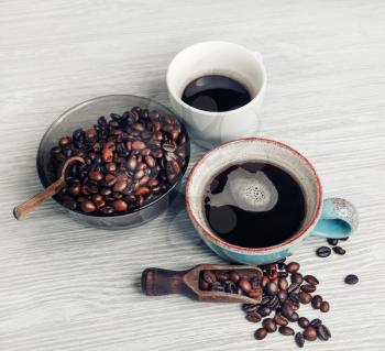 Coffee cups and coffee beans on light wood kitchen table background. Still life with coffee.