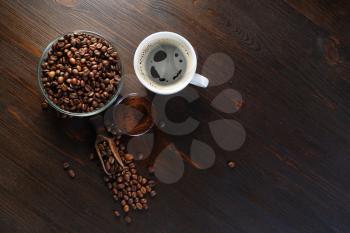 Fresh tasty coffee. Coffee cup, coffee beans and ground powder on wooden background. Top view. Flat lay.