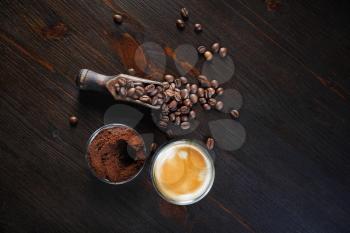 Photo of coffee espresso cup, roasted coffee beans and ground powder against wooden table background. Top view. Flat lay.